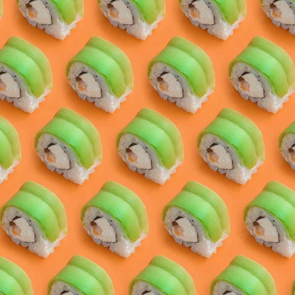 Rolos de sushi vegetariano com abacate e queijo filadélfia em fundo laranja. Minimalismo vista superior plano leigos padrão com comida japonesa — Fotografia de Stock