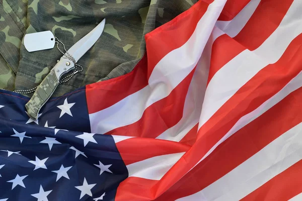 Army dog tag token and knife lies on Old Camouflage uniformis és hajtogatott United States Flag — Stock Fotó