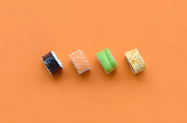 Diferentes tipos de rollos de sushi asiático sobre fondo naranja. Minimalismo vista superior plana laico con comida japonesa —  Fotos de Stock