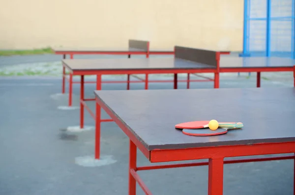 Raquettes et ballon sur la table de ping-pong dans la cour de sport extérieure. Concept de sport actif et d'entraînement physique — Photo