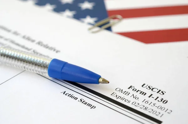 I-130 Petition for alien relative blank form lies on United States flag with blue pen from Department of Homeland Security — 스톡 사진