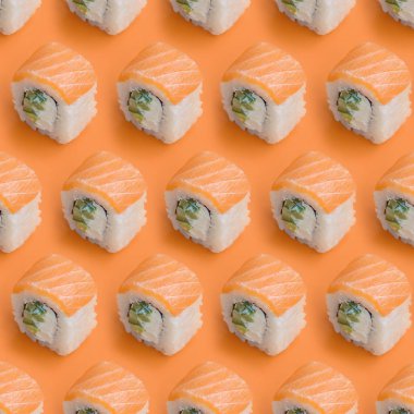 Philadelphia turuncu arka planda somon balığıyla yuvarlanıyor. Minimalizm üst görünüm düz Japon yemekleri ile yatıyordu