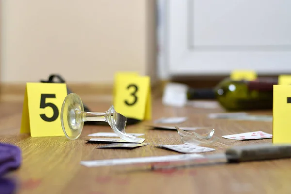 Investigación de la escena del crimen - numeración de las pruebas después del asesinato en el apartamento. Copa rota de vino, cuchillo y botella como evidencia —  Fotos de Stock