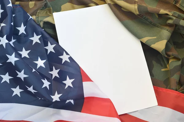 Blank paper lies on United States of America flag and folded military uniform jacket. Military symbols conceptual background banner and copy space — Stock Photo, Image