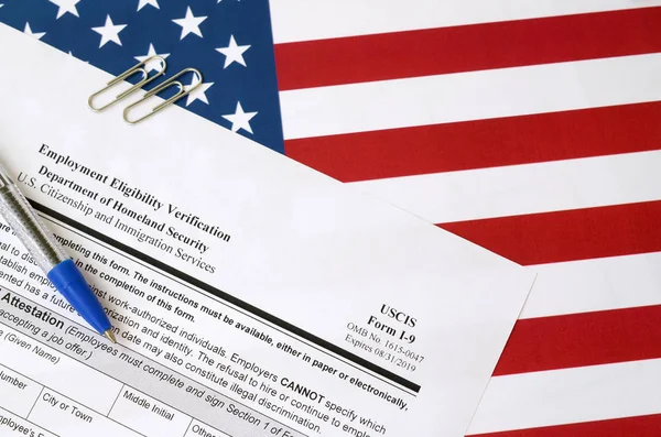 I-9 Employment Eligibility Verification blank form lies on United States flag with blue pen from Department of Homeland Security — 스톡 사진