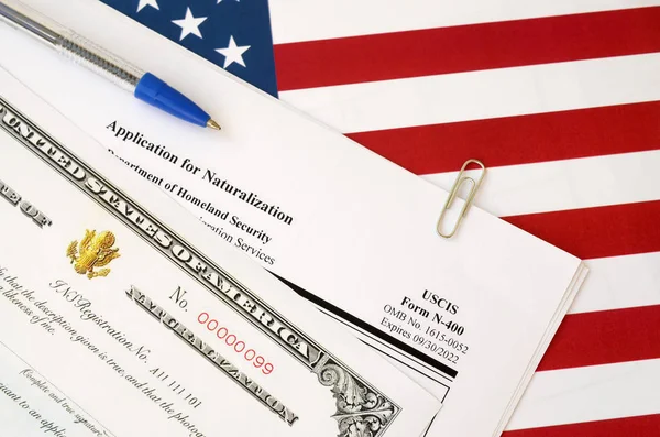 N-400 pedido de naturalização e certificado de naturalização encontra-se na bandeira dos Estados Unidos com caneta azul do Departamento de Segurança Interna — Fotografia de Stock