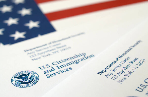 Конверты с письмом от USCIS на флаге США от Министерства внутренней безопасности
