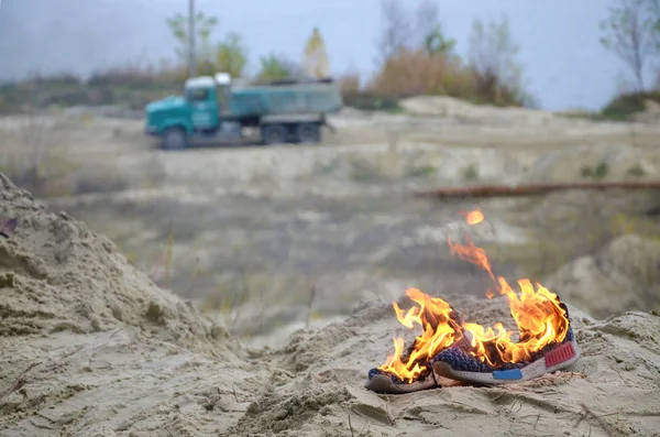 Brennende Turnschuhe oder Turnschuhe stehen am Sandstrand in Flammen. Sportler verbrannte. Körperliche Anstrengung beim Trainingskonzept — Stockfoto