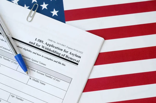 I-589 Wniosek o udzielenie azylu i o wstrzymanie wydalenia pusty formularz znajduje się na fladze Stanów Zjednoczonych z niebieskim długopisem z Departamentu Bezpieczeństwa Wewnętrznego — Zdjęcie stockowe