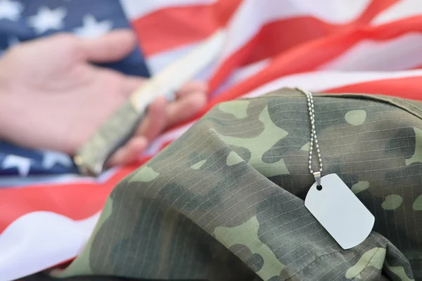 Dog tags lies with hand of man who commit suicide with a knife — Stock Photo, Image