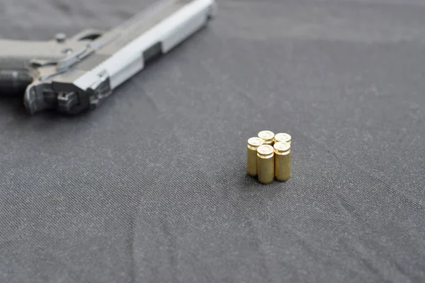 Balas de 9mm e pistola estão em um tecido preto. Um conjunto de itens gama de tiro ou um kit de auto-defesa — Fotografia de Stock