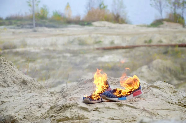 Brennende Turnschuhe oder Turnschuhe stehen am Sandstrand in Flammen. Sportler verbrannte. Körperliche Anstrengung beim Trainingskonzept — Stockfoto