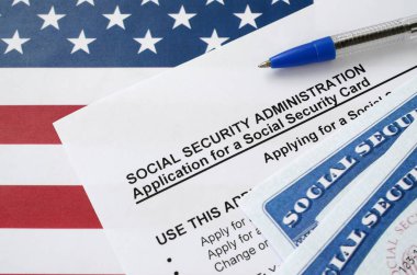 Birleşik Devletler Sosyal Güvenlik Kartları, Amerikan bayrağında mavi kalemle Sosyal Güvenlik Yönetiminin Uygulamasında yatıyor.