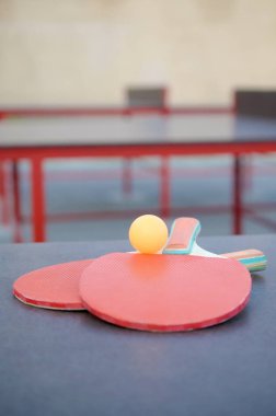 Raketler ve top dışarıdaki spor sahasında masa tenisi masasında. Aktif spor ve beden eğitimi konsepti
