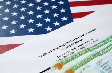 I-485 Application to register permanent residence or adjust status form and green card from dv-lottery lies on United States flag from Department of Homeland Security clipart