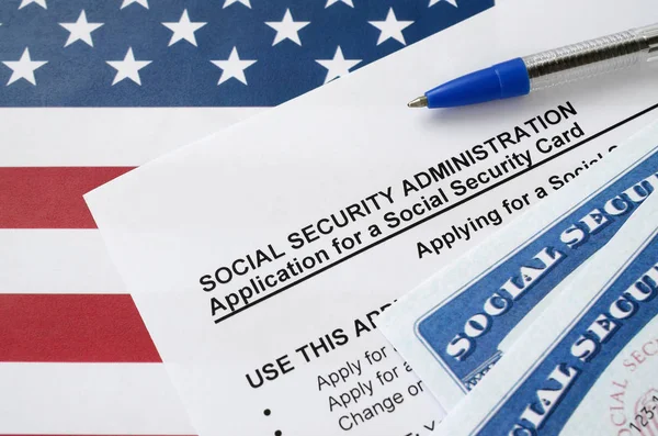 United States social security number cards lies on Application from social security administration with blue pen on US flag — 스톡 사진