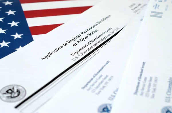 I-485 Application to register permanent residence or adjust status blank form lies on United States flag with envelope from Department of Homeland Security — 스톡 사진