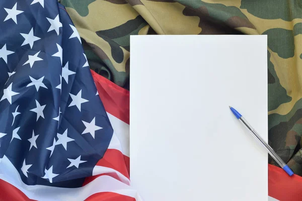 El papel en blanco yace en la bandera de los Estados Unidos de América y la chaqueta de uniforme militar plegada. Banner de fondo conceptual de símbolos militares y espacio de copia — Foto de Stock