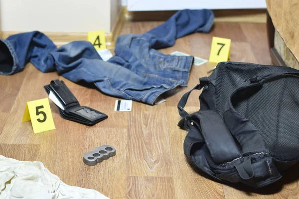 Investigación de la escena del crimen - numeración de las pruebas después del asesinato en el apartamento. Nudillos, billetera y ropa de latón con marcadores de evidencia —  Fotos de Stock