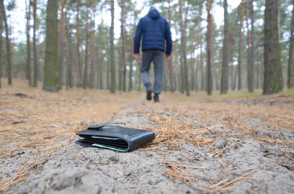 Young man loses his purse with euro money bills on Russian autumn fir wood path. Carelessness and losing wallet concept — 스톡 사진