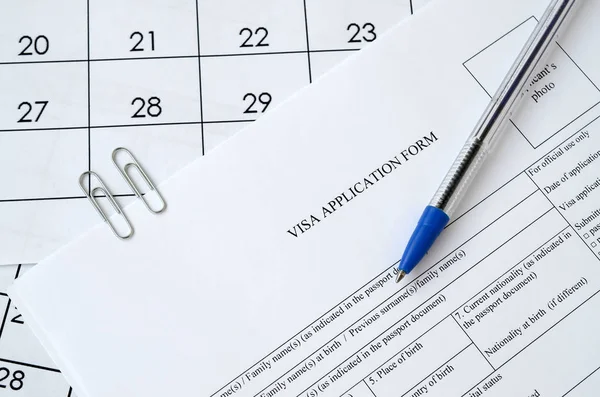 Typisch visumaanvraagformulier en blauwe pen op papieren kalenderpagina — Stockfoto