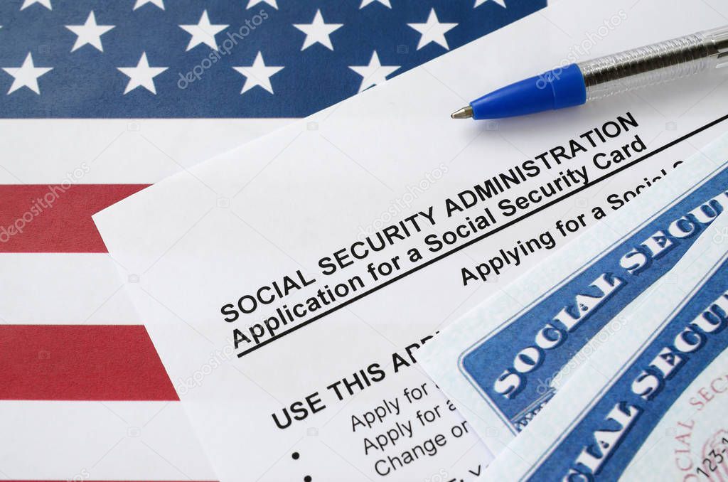 United States social security number cards lies on Application from social security administration with blue pen on US flag