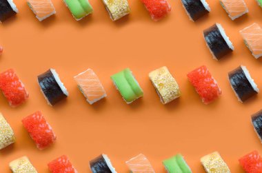 Turuncu arka planda farklı Asya suşi çeşitleri var. Minimalizm üst görünüm düz Japon yemekleri ile yatıyordu