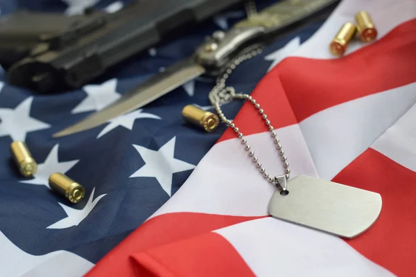 Jeton d'étiquette de chien de l'armée avec des balles de 9mm et le pistolet reposent sur le drapeau plié des États-Unis — Photo
