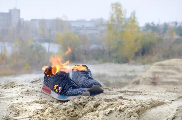 Burning sports sneakers or gym shoes on fire stand on sandy beach coast. Athlete burned out. Physical exertion during training concept — 스톡 사진