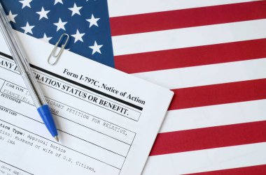 I-797c Notice of action blank form lies on United States flag with blue pen from Department of Homeland Security clipart