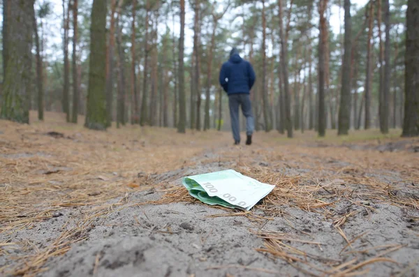 O jovem perde as suas notas de euro no caminho da madeira de abeto do Outono russo. Descuido e perda de conceito de dinheiro — Fotografia de Stock
