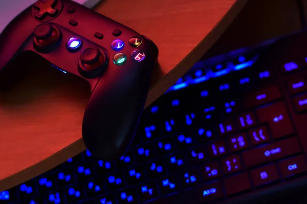 Modernes Gamepad liegt mit PC-Tastatur auf dem Tisch in dunkler Spielzimmerszene. Videospiel-Speedrun-Konzept oder Wettkampfherausforderung — Stockfoto