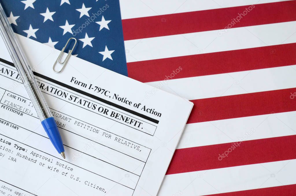 I-797c Notice of action blank form lies on United States flag with blue pen from Department of Homeland Security