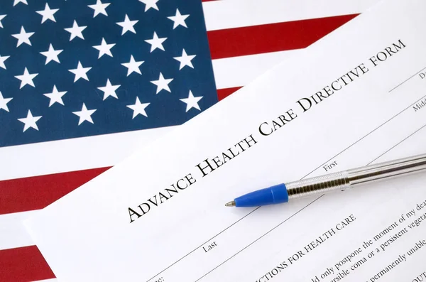 Adiantamento de cuidados de saúde formulário em branco directiva e caneta azul na bandeira dos Estados Unidos — Fotografia de Stock