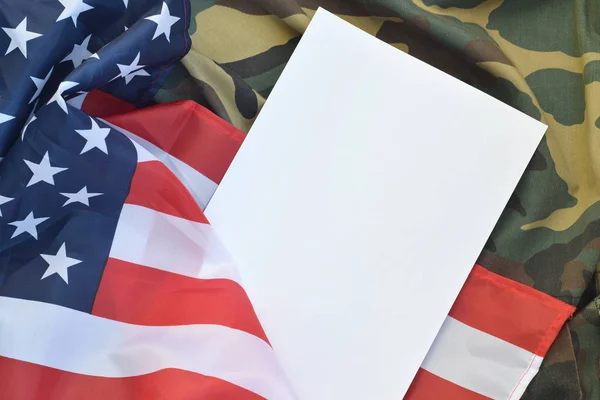 ブランクペーパーはアメリカの国旗と折り畳まれた軍の制服ジャケットにある。軍事シンボルの概念的背景バナーとコピースペース — ストック写真