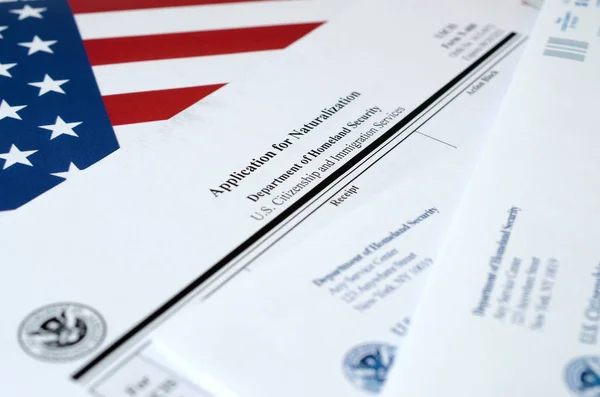 N-400 Demande de naturalisation formulaire vierge se trouve sur le drapeau des États-Unis avec enveloppe du ministère de la Sécurité intérieure — Photo