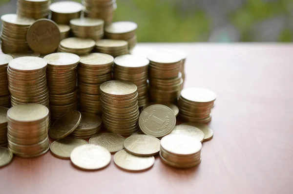 Grande quantità di lucido ucraino vecchio 1 hryvnia coin stack da vicino su tavolo di legno su sfondo alberi verdi. Il concetto di business e ricca vita in Ucraina — Foto Stock