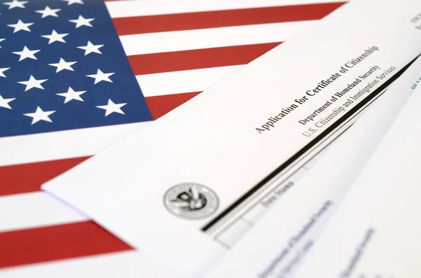 N-600 Застосування для сертифікату про громадянство порожня форма лежить на прапорі Сполучених Штатів з конвертом від Департаменту національної безпеки — стокове фото