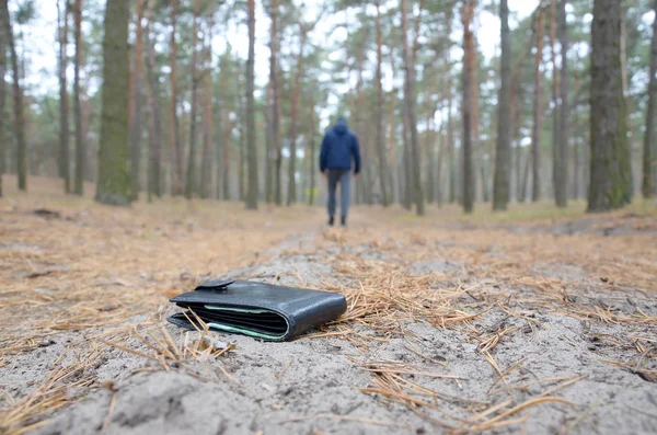 Young man loses his purse with euro money bills on Russian autumn fir wood path. Carelessness and losing wallet concept — Stock Photo, Image