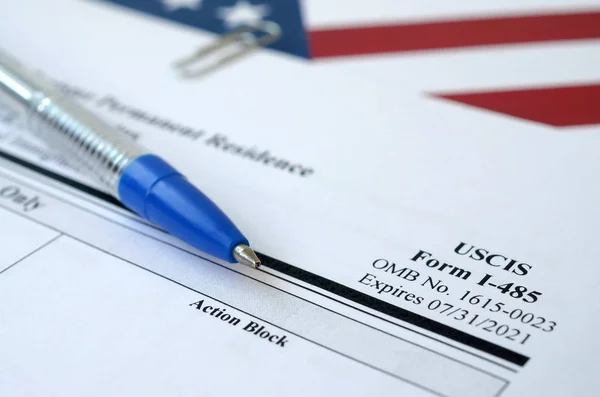 I-485 Застосування для реєстрації постійного проживання або коригування статусу порожньої форми лежить на прапорі Сполучених Штатів з синьою ручкою від Департаменту національної безпеки — стокове фото