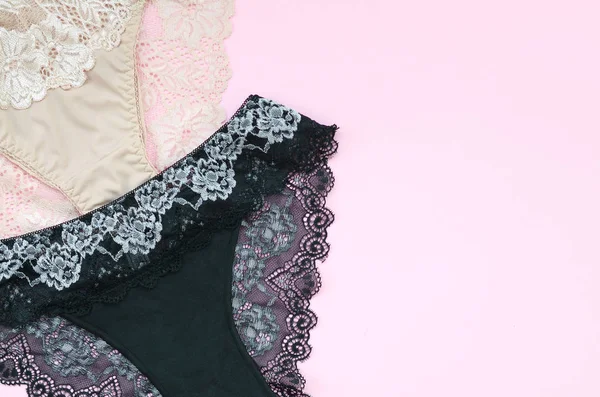 White, black and pink women underwear with lace on pink background with copy space. Advertising for shop of beautiful and comfortable women underwear