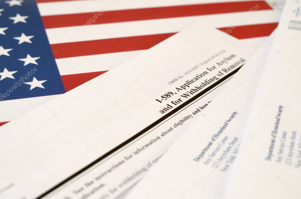 I-589 Application for asylum and for withholding of removal blank form lies on United States flag with envelope from Department of Homeland Security