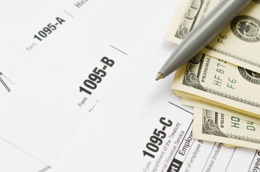 Irs Form 1095-A 1095-B ve 1095-C boş takvim sayfasında dolarlar ve dolarlar var.