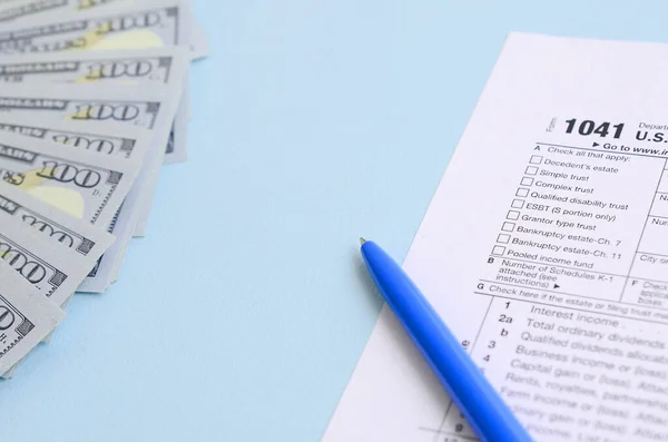 1041 formulário de imposto encontra-se perto de notas de cem dólares e caneta azul em um l — Fotografia de Stock