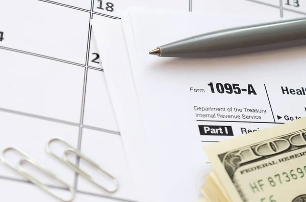 Irs Form 1095-A Health Insurance Marketplace Statement tax blank ligger med penna och många hundra dollarsedlar på kalendersidan — Stockfoto