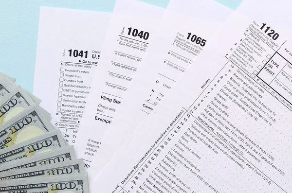 Formulários fiscais encontra-se perto de notas de cem dólares e caneta azul em uma luz — Fotografia de Stock