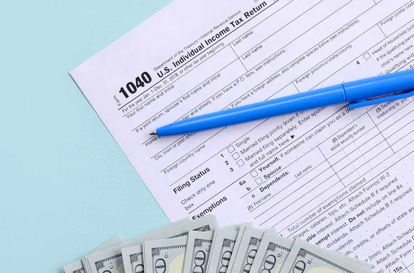 1040 tax form lies near hundred dollar bills and blue pen on a l — 스톡 사진