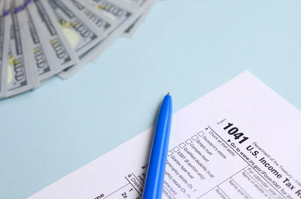 1041 tax form lies near hundred dollar bills and blue pen on a l — Stock Photo, Image