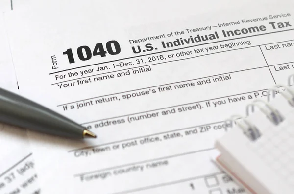 The pen and notebook is lies on the tax form 1040 U.S. Individua — Stock Photo, Image