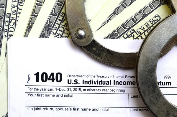 Polizeihandschellen liegen auf dem Steuerformular 1040. — Stockfoto